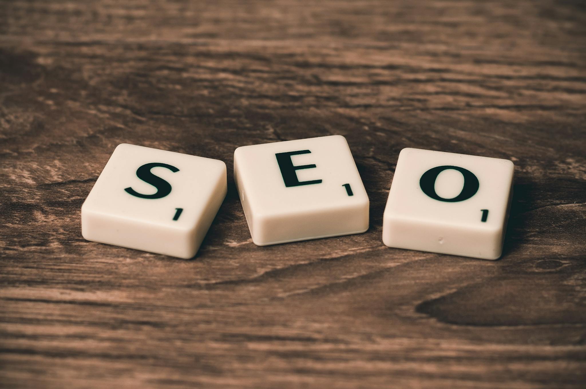 Nitish Verma Books 1 Scrabble tiles spelling 'SEO' on a wooden surface. Ideal for digital marketing themes.